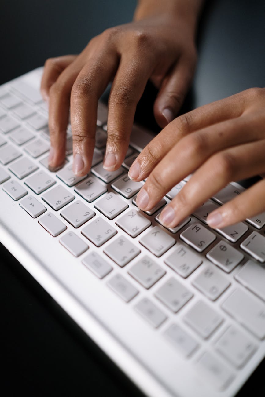 persons hand on white computer keyboard